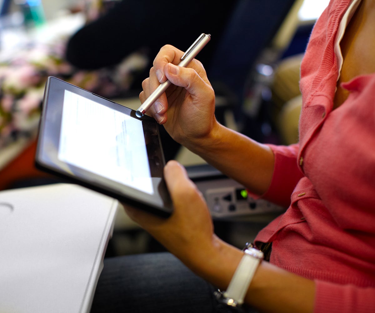 民間航空機の機内でiPadを使用する人