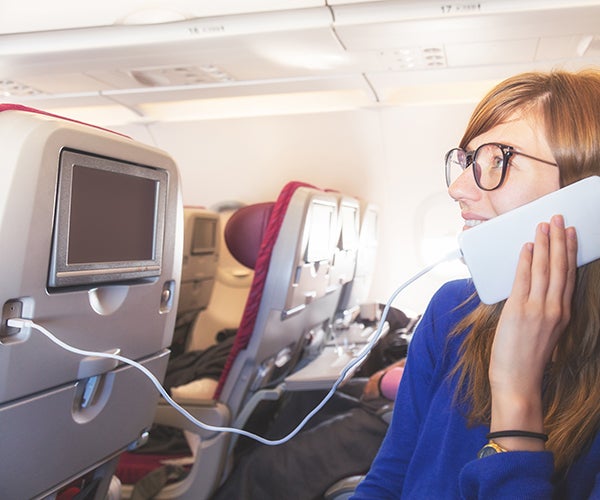 Woman charging her phone on a USB at-seat module
