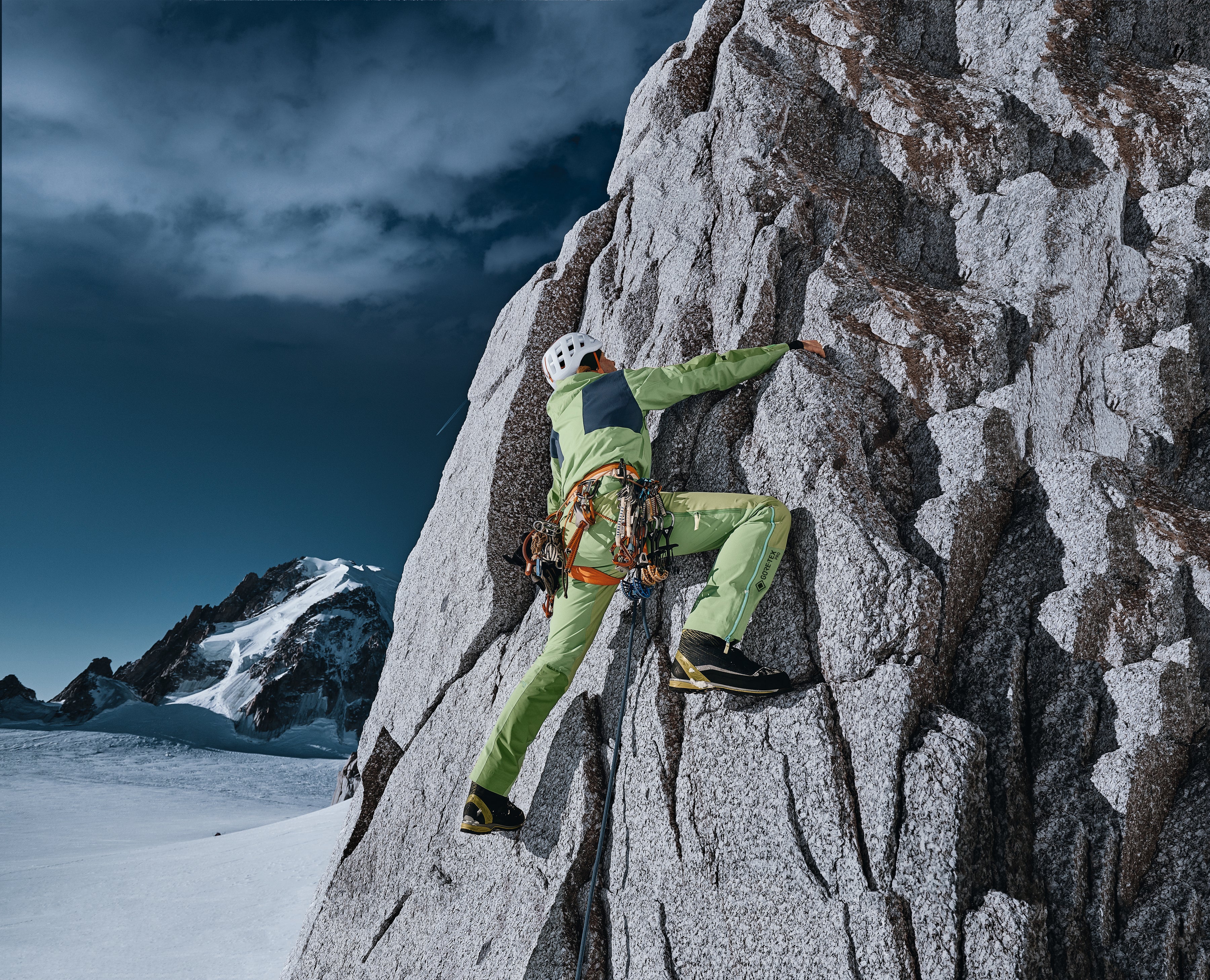 Person climbing steep cliffside in hi-vis workwear