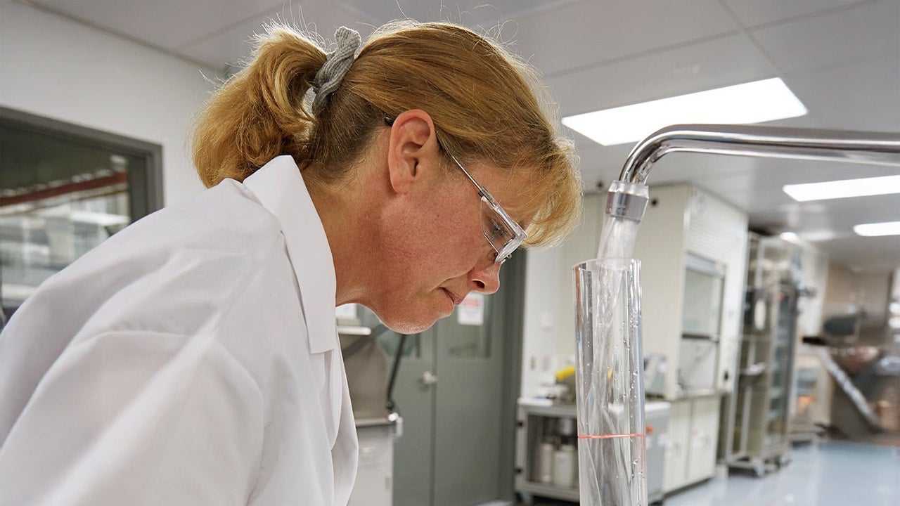 Woman examining a sample in a laboratory.