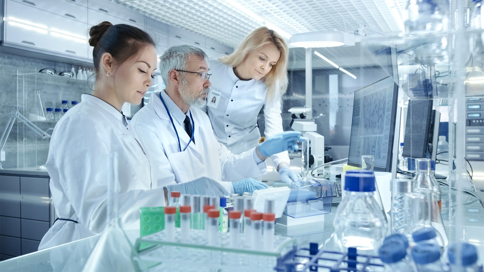 Three healthcare professionals in a lab examining samples.