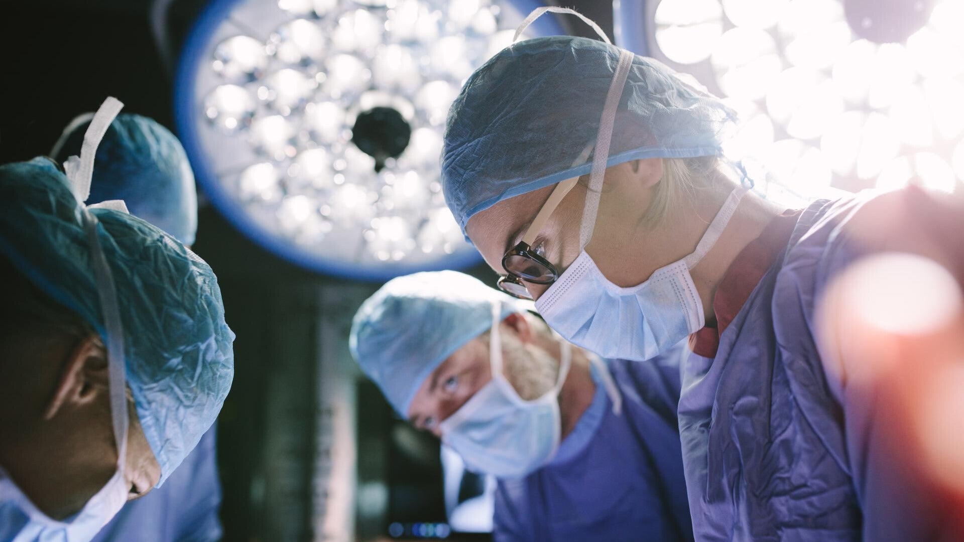 doctors in operating room with bright lights