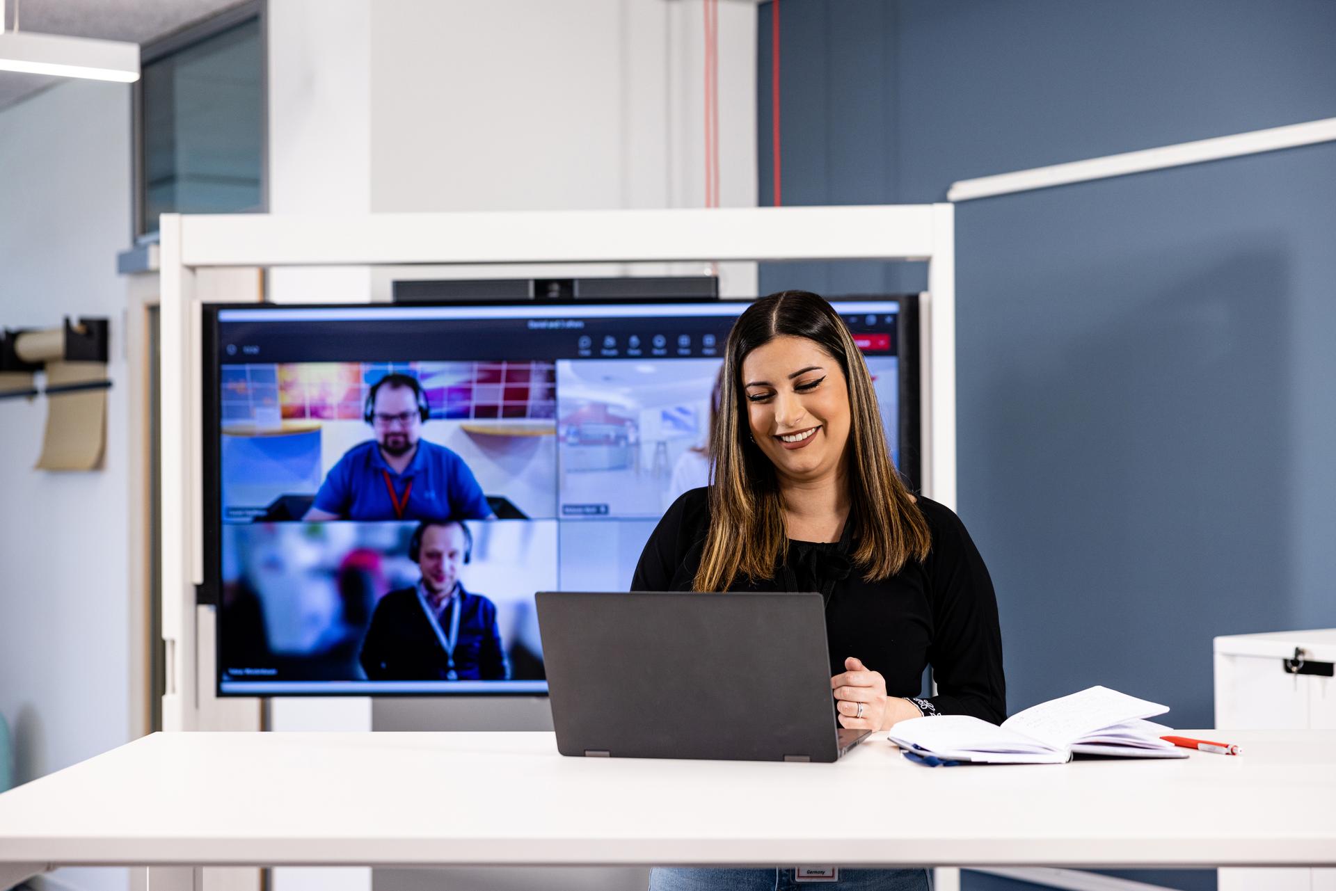 associate in a meeting space with other associates on video conference
