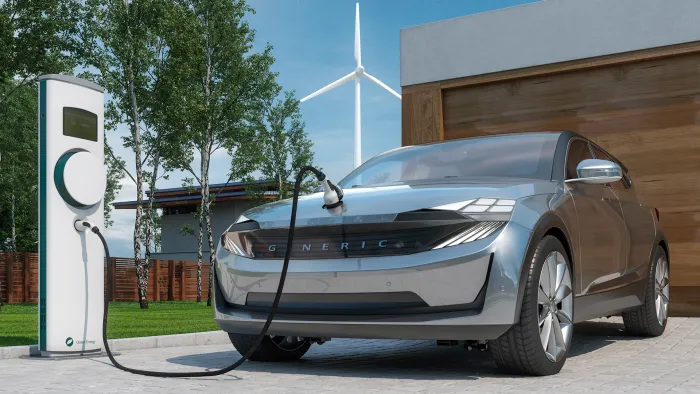 郊外のモダンな住宅の前で充電する電動SUV